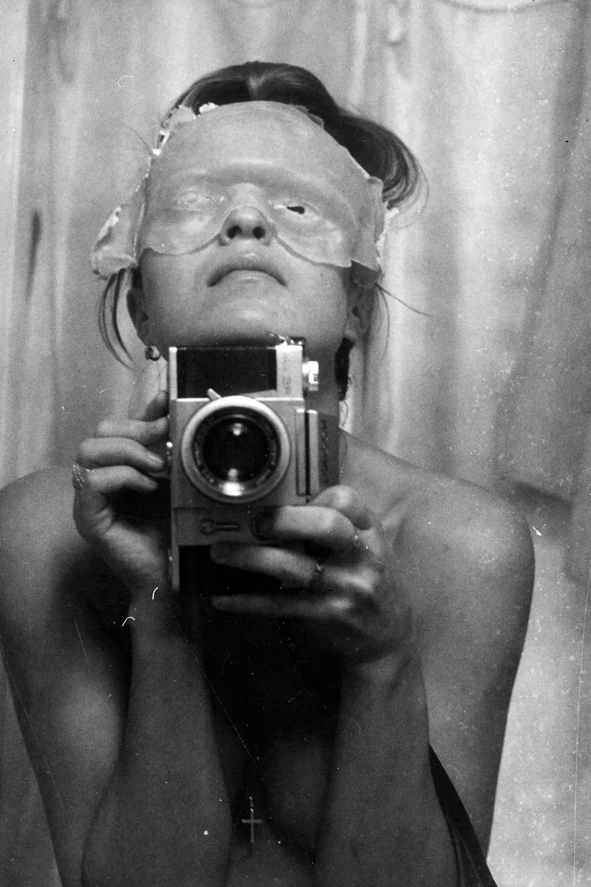 Birgit Jürgenssen, Self-portrait with Mask (Selbstporträt mit Maske), 1974, b/w photograph, 40 x 30 cm. Private collection, Vienna © Estate Birgit Jürgenssen / Bildrecht Vienna, 2026; Courtesy Galerie Hubert Winter